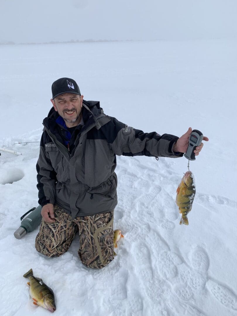 A man holding a fish in the snow.