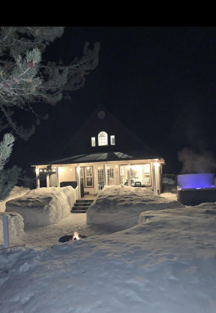 A house with snow on the ground and a fire pit in front of it.