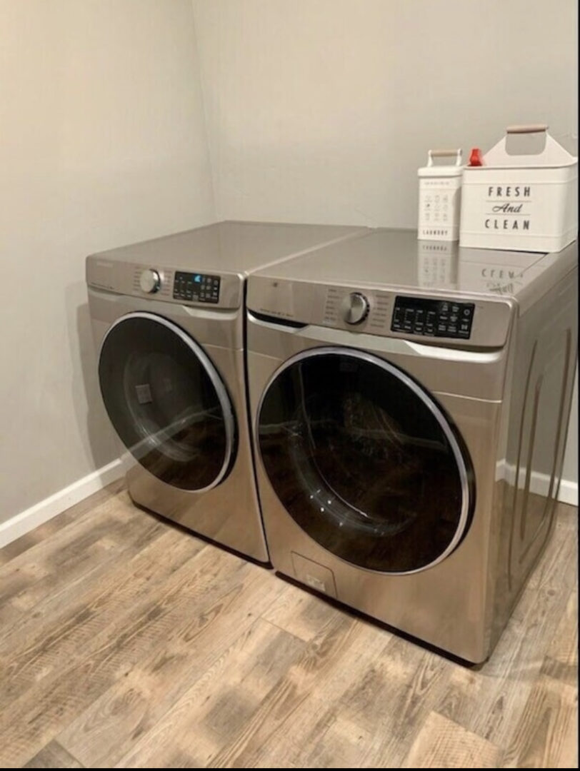 A pair of silver washer and dryer in a room.